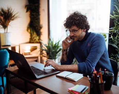 Young man talking on the phone in his home office Young man talking on the phone in his home office