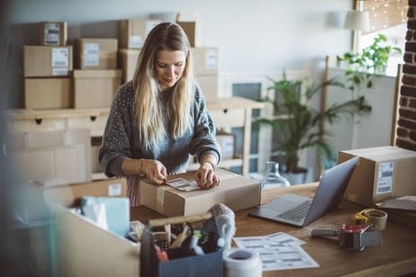Working woman at online shop. She is wearing casual clothing and packaging goods for delivery
