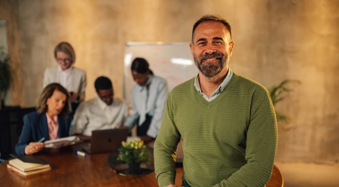 Smiling businessman looking at camera on meeting of interracial team